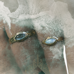 Two decorative earrings with gemstones on a textured surface