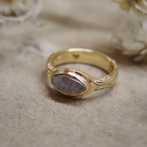 Gold ring with a stone on a textured surface