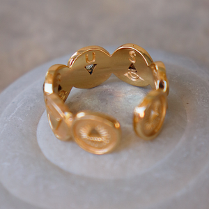Gold ring with intricate design on a reflective surface