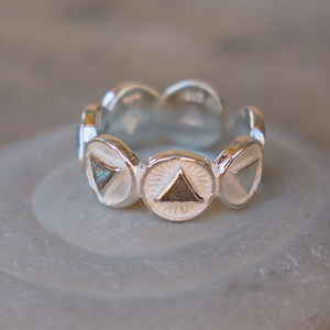 Silver ring with geometric designs on a textured surface