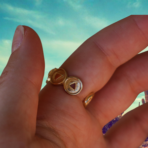 Gold ring  held between fingers with a blurred natural background